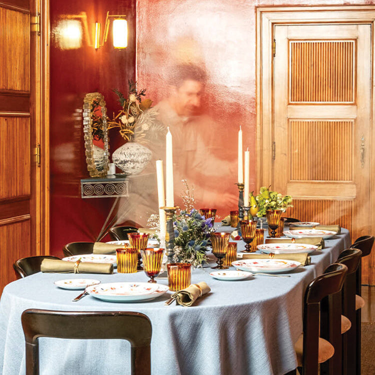Dining table set for a meal with candles and decorative items in a warmly lit room.