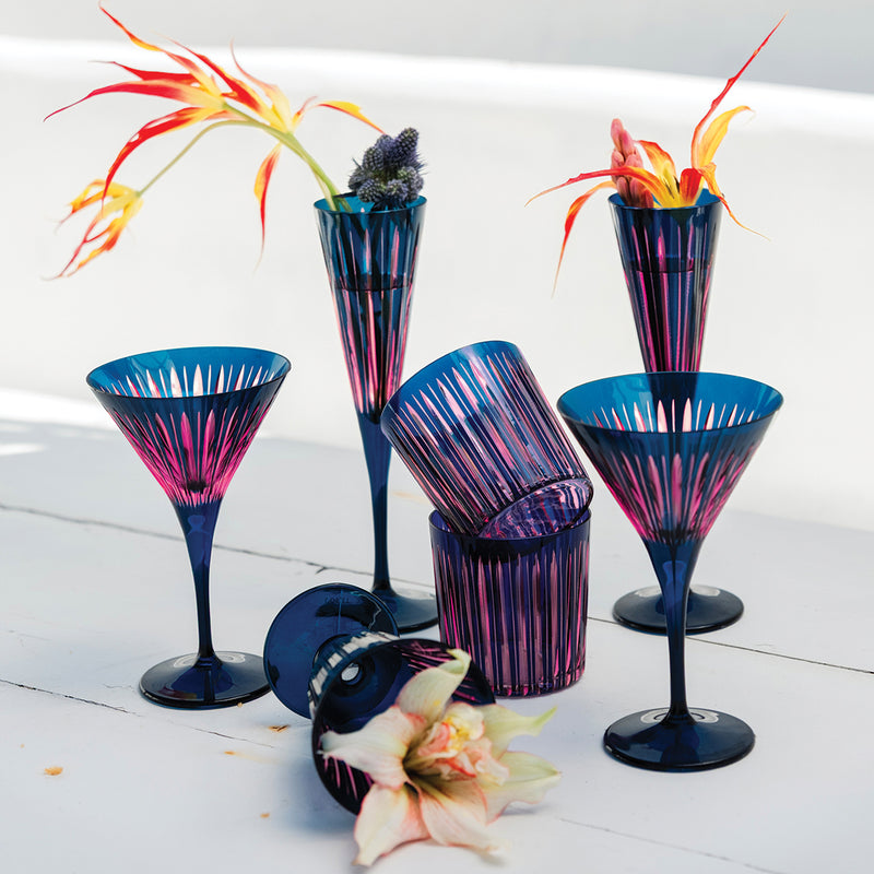 Set of colorful cocktail glasses with floral decorations on a white surface