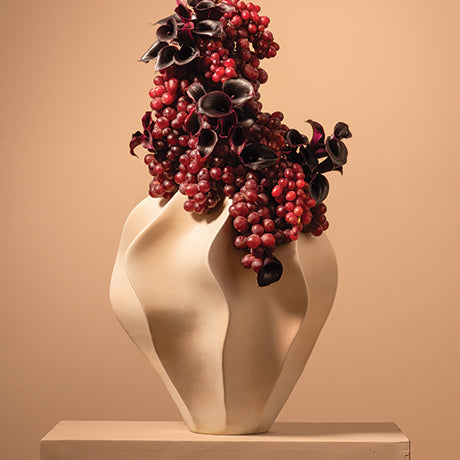 Decorative vase with red berries and black leaves on a beige background