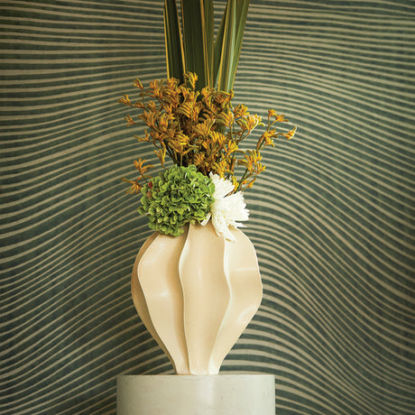 Decorative vase with flowers against a wavy green and beige wall