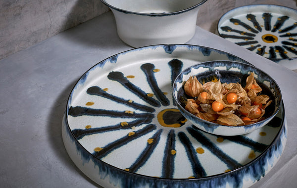 Decorative round platters and serving bowls with hand-painted gold and blue sunburst motif.