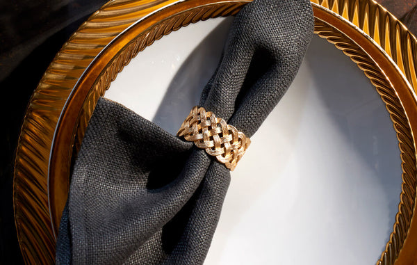 Gold braided napkin jewel on dark grey napkin.