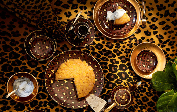 Maximalist tabletop includes gold leopard print table linens, pineapple cake served on leapoard print porcelain cake plate, leopard print teacups and saucers.