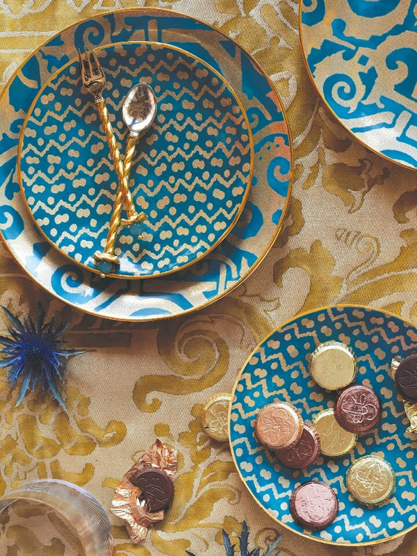 Decorative plates with blue and gold patterns on a patterned tablecloth.