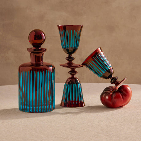Set of glass decanters with blue and red design on a beige surface and background