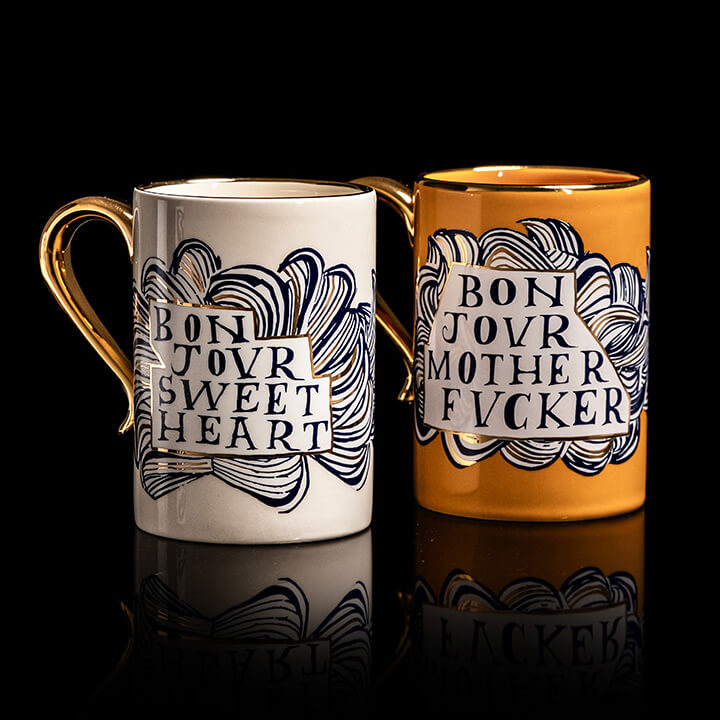 Two mugs with text design on a black background