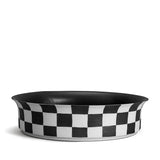Damier Bowl - Large. Black and white checkerboard glaze pattern on a low, round porcelain bowl with a flared rim shape. Black glazed interior.