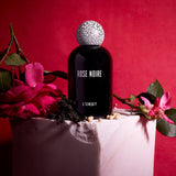 black bell shaped glass bottle with round crackle top styled with a moody red background
