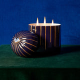 blue Lito Candle 3-wick lit up with eye motif styled with a green and blue background.
