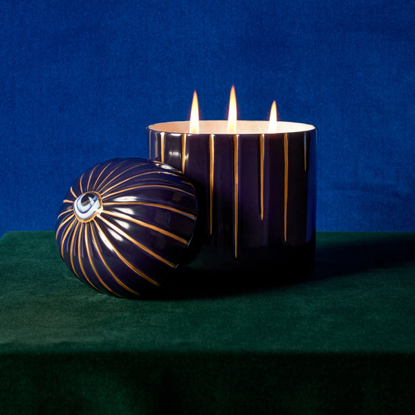 blue Lito Candle 3-wick lit up with eye motif styled with a green and blue background.