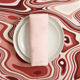 Linen tablecloth with an organic, undulating pattern in red, pink and ivory hues. Terra stone glazed dinnerware.
