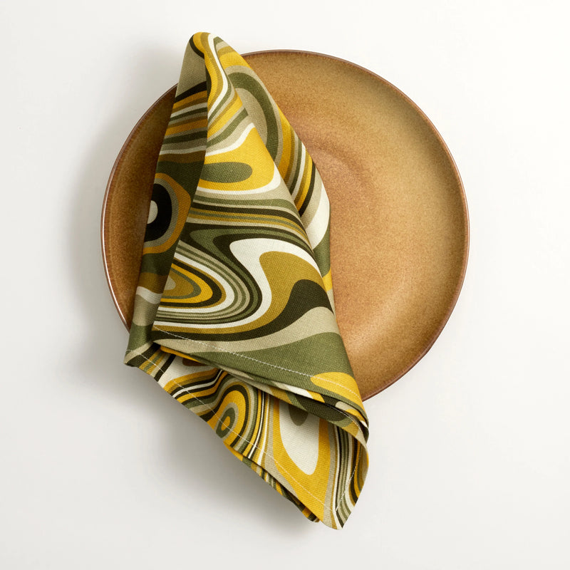 Terra leather glazed dinner plate, Linen napkins with an organic, psychedelic pattern in muted green, yellow, brown and ivory hues.